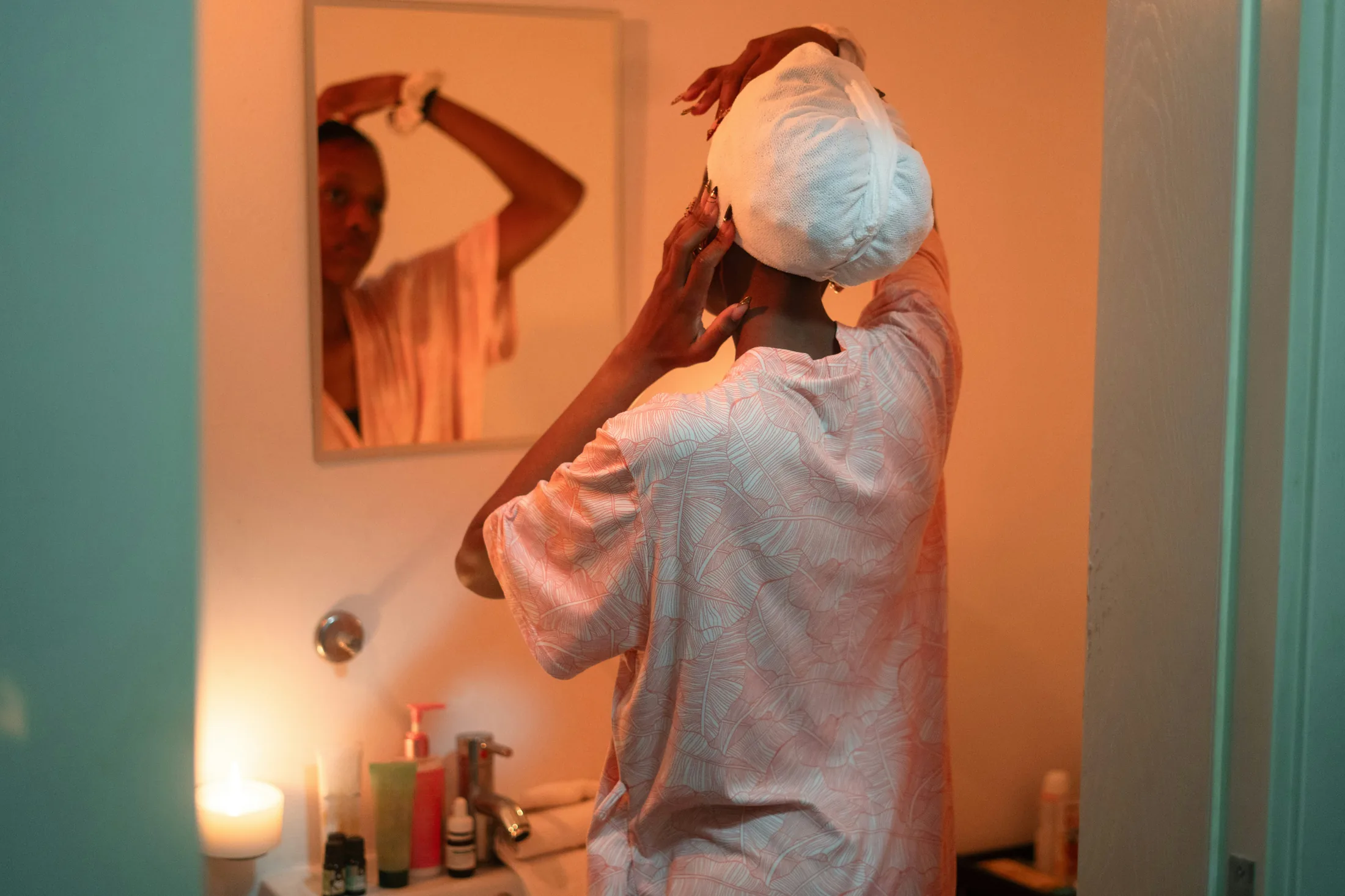 Woman caring for her hair in a bathroom mirror
